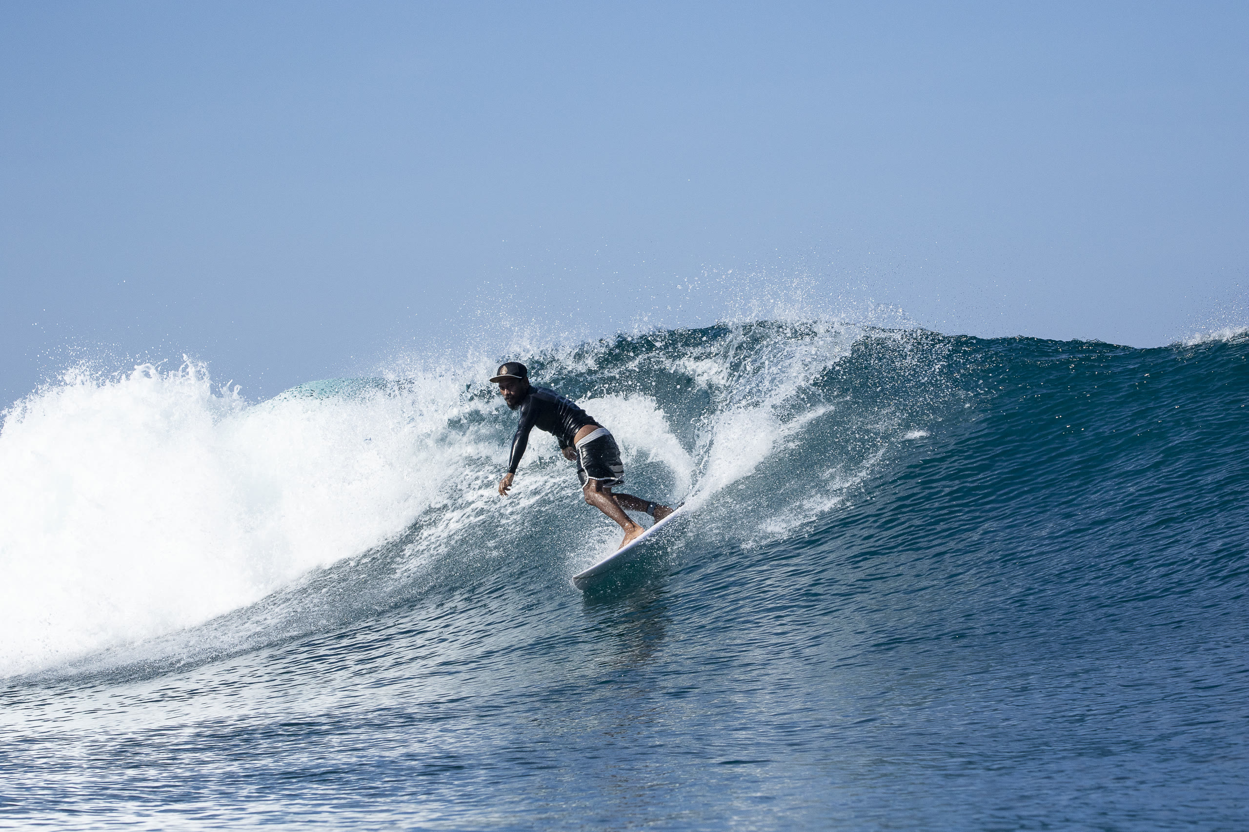 Surfer dropping into a blue barrel wave at Kuta Reef, Bali